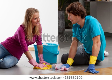 A couple cleaning the floor with dusters and lather