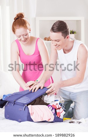 Couple try to close over packed luggage