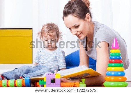A young woman looking at some family pictures with her little son