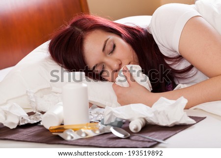 Sick woman sleeping in bed next to cold medicine