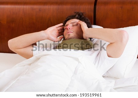 Sick man suffering from headache in bed