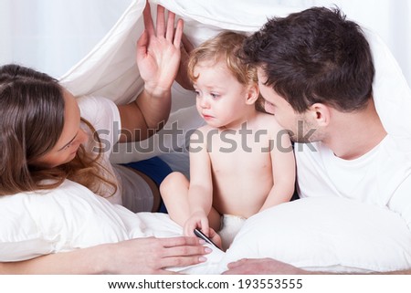 A family of loving parents and a sad baby having their time in bed