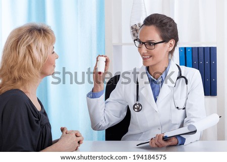 Smiling doctor giving pills to a middle aged patient