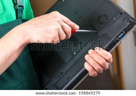 Hands repairing a laptop with a screwdriver