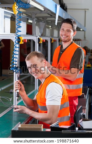 Factory worker teaching new employee how to work on the production line