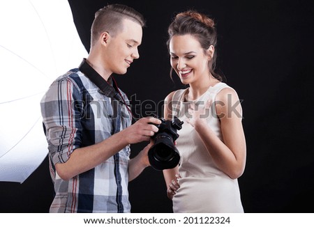 Man with camera showing photo to attractive female model