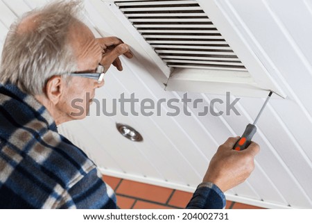 Man tightening the bolts on ventilation grille, horizontal