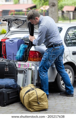 Vertical view of a man packing car for vacation