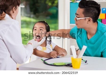 Asian girl during throat examination at doctor\'s office