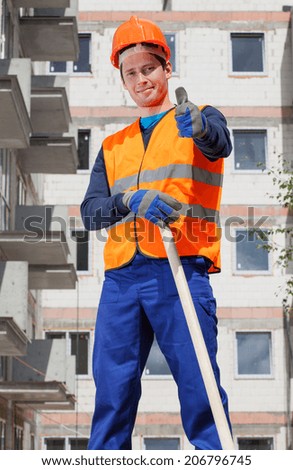 Builder in protective vest and hardhat showing thumbs up sign