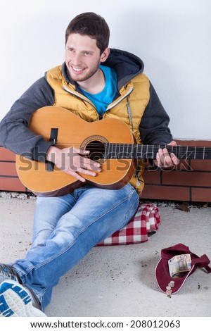 Guitarist collecting money on the street, vertical
