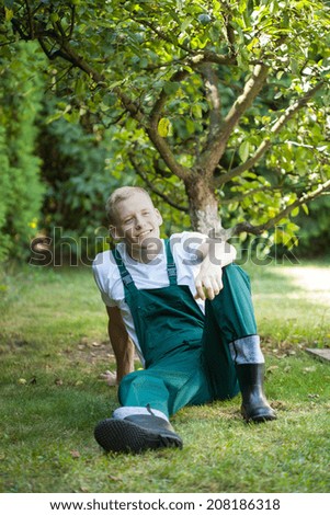Gardener resting in orchard after work, vertical