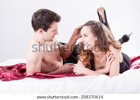 Young smiley couple lying on big bed