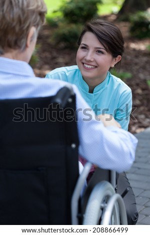 Young nurse talking with elderly disabled woman