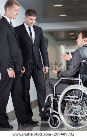 Businessman on wheelchair during small talk with his colleagues from company
