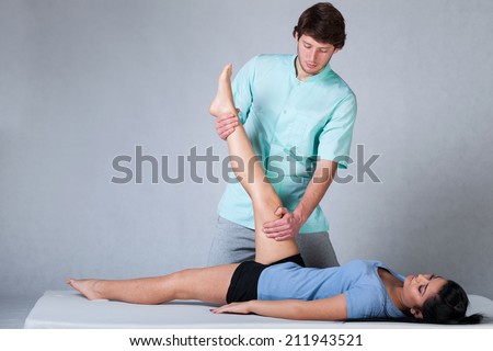 Physiotherapist stretching patient with shortened hamstring muscles