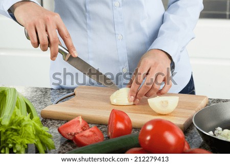 Woman cutting onion to prepare tasty dinner