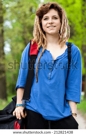 Smiling teenage girl with travel bag outside