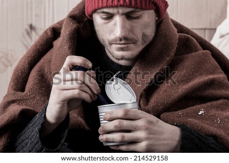 Frozen homeless man eat food from cans