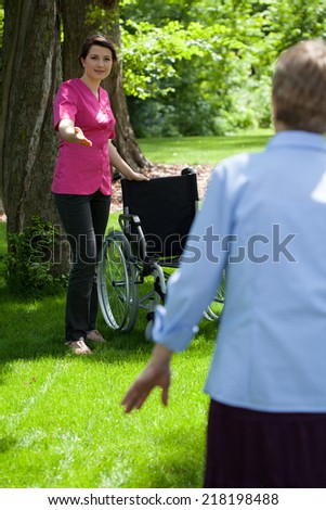 Nurse with elderly woman in garden of retirement home, vertical