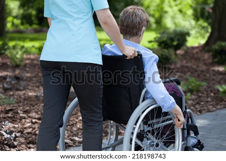 Close-up of a nurse pushing elderly woman on wheelchair
