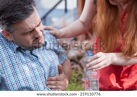 Woman giving water man with chest pain