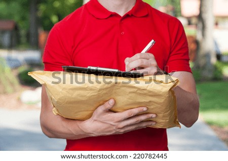 Delivery man filling in forms on parcel
