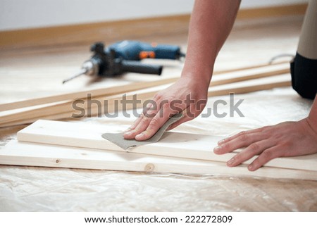 Male hands polishing wooden plank with sandpaper