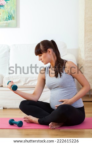 Pregnant woman during training with dumb-bells, vertical