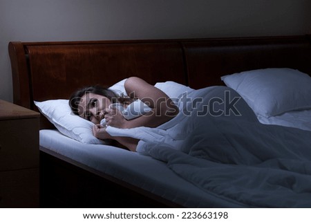 Terrified woman lying in bed at night