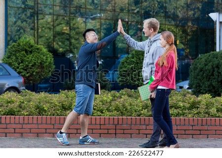 Asian young man giving friend a high five