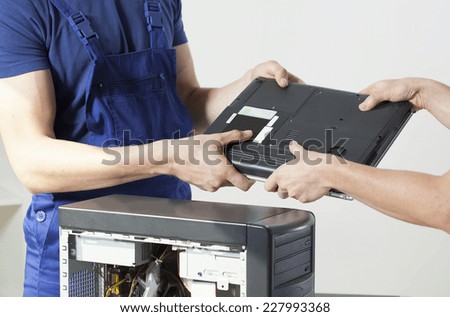 Computer technician's hands giving client repaired laptop
