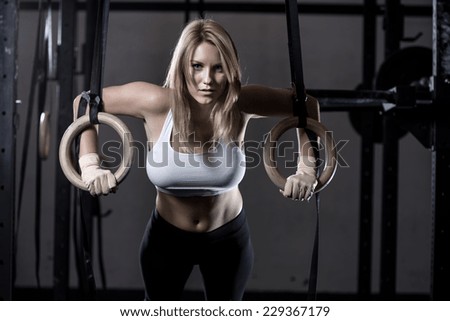 Young fit girl pulling up on a gimnastic rings