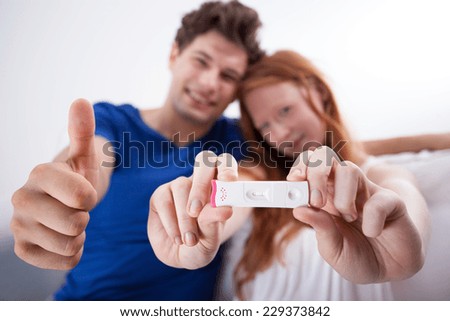 Happy young married couple holding positive pregnancy test