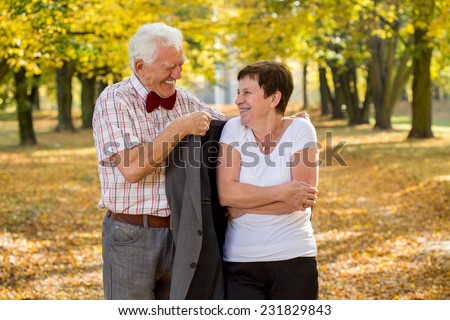 Elderly happy man giving the coat to his freezing wife