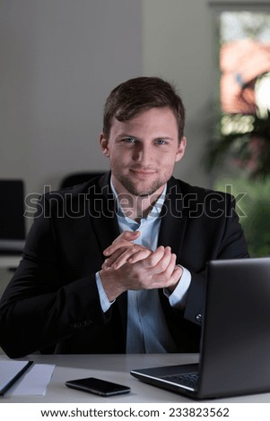 Young attractive happy employee at his workplace