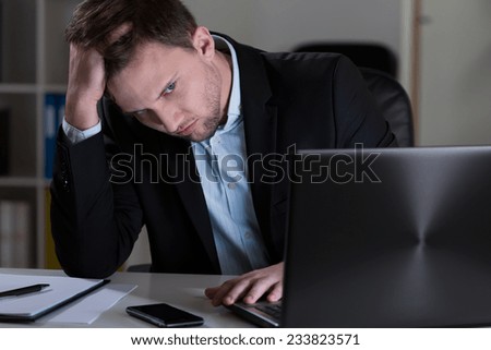 Young handsome tired man working at night in his office