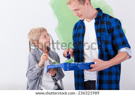 Young father painting wall with son, horizontal