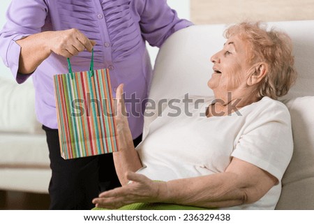 Sick elderly woman getting the gift from her old good friend