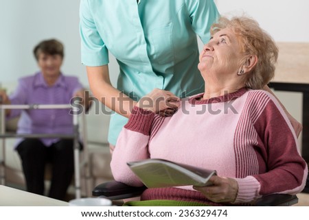 Young caring therpist and senior woman in nursing home