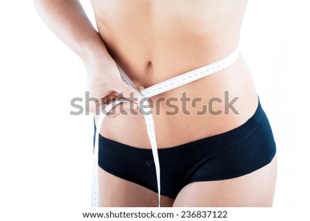 Young slim woman measuring her waistline