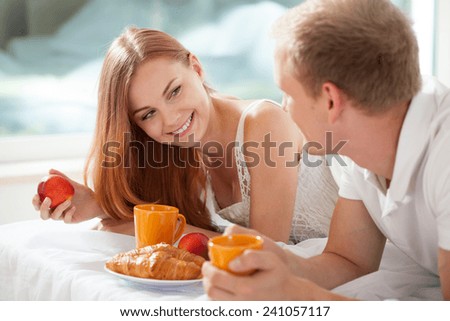 Young married couple and breakfast in bedroom