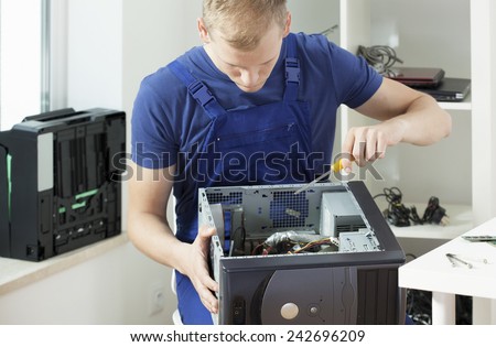 Young handsome man trying to repair his broken computer