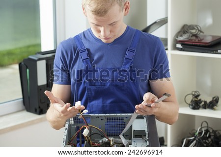 Young confused computer specialist reparing broken computer