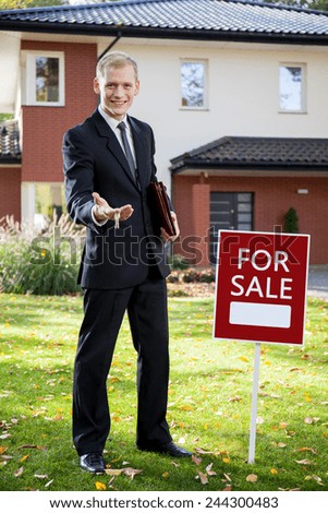Young handsome real estate agent holding the keys to house for sale