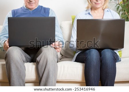 Aged couple sitting together with theirs computers
