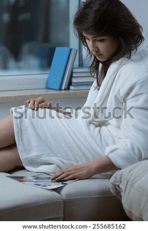 Young pretty depressed woman looking at old photo