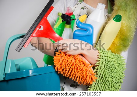 Close-up of woman holding a lot of cleaning tools