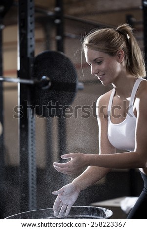Young girl prepares to weightlifting using the talcum powder