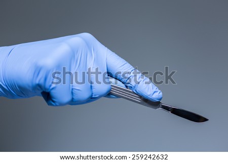 Close-up of scalpel in the hand in glove of doctor